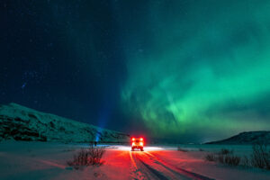 A glowing vehicle under the northern lights on a snowy night, capturing the breathtaking beauty of Iceland winter magic.