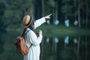"Independent female traveler pointing towards nature near a serene lake, representing the Best Destinations for Independent Travelers."