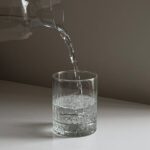 A clear glass of fresh drinking water on a table, highlighting the importance of staying hydrated for good health.