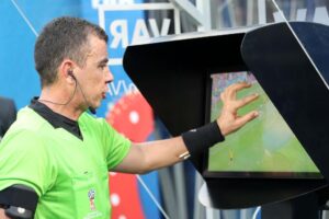 How VAR Has Changed Football Forever as a football referee reviews a decision using the VAR monitor during a match.