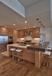 Beautiful contemporary kitchen with a built-in microwave oven, white countertops, wooden finishes, and pendant lighting.