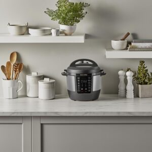 Modern Instant Pot electric pressure cooker displayed on a stylish white kitchen counter with shelves and kitchen accessories.