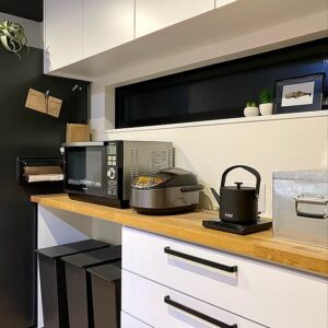 Contemporary kitchen design showcasing sleek black and white appliances on a wooden countertop with clean, modern interiors.