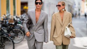 Fashion Trends Inspired by Social Media showcasing two women wearing oversized blazers and stylish streetwear outfits, highlighting influencer-driven fashion and modern urban style trends.